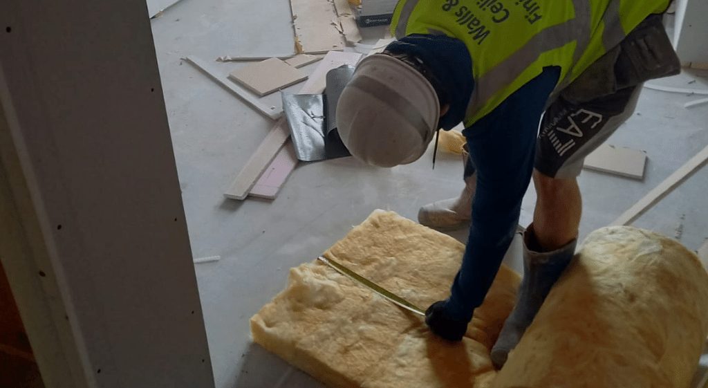 A worker measuring wool insulation during an observation for his Floor Insulation NVQ